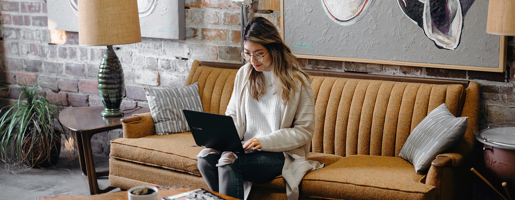 resident sits on cafe couch and works on her laptop